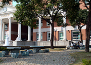 Stone tables under trees at right-hand side of front square of Humanities and Management Building