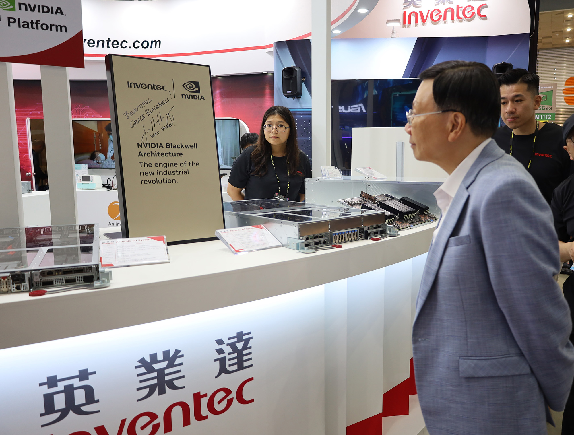 President Jeffrey J.P. Tsai of Asia University (right) at Inventec's booth during COMPUTEX, observing NVIDIA co-founder Jensen Jen-hsun Huang 's signature on the latest NVIDIA GB200 NVL72 AI cabinet used by manufacturing partner Inventec, learning about its applications