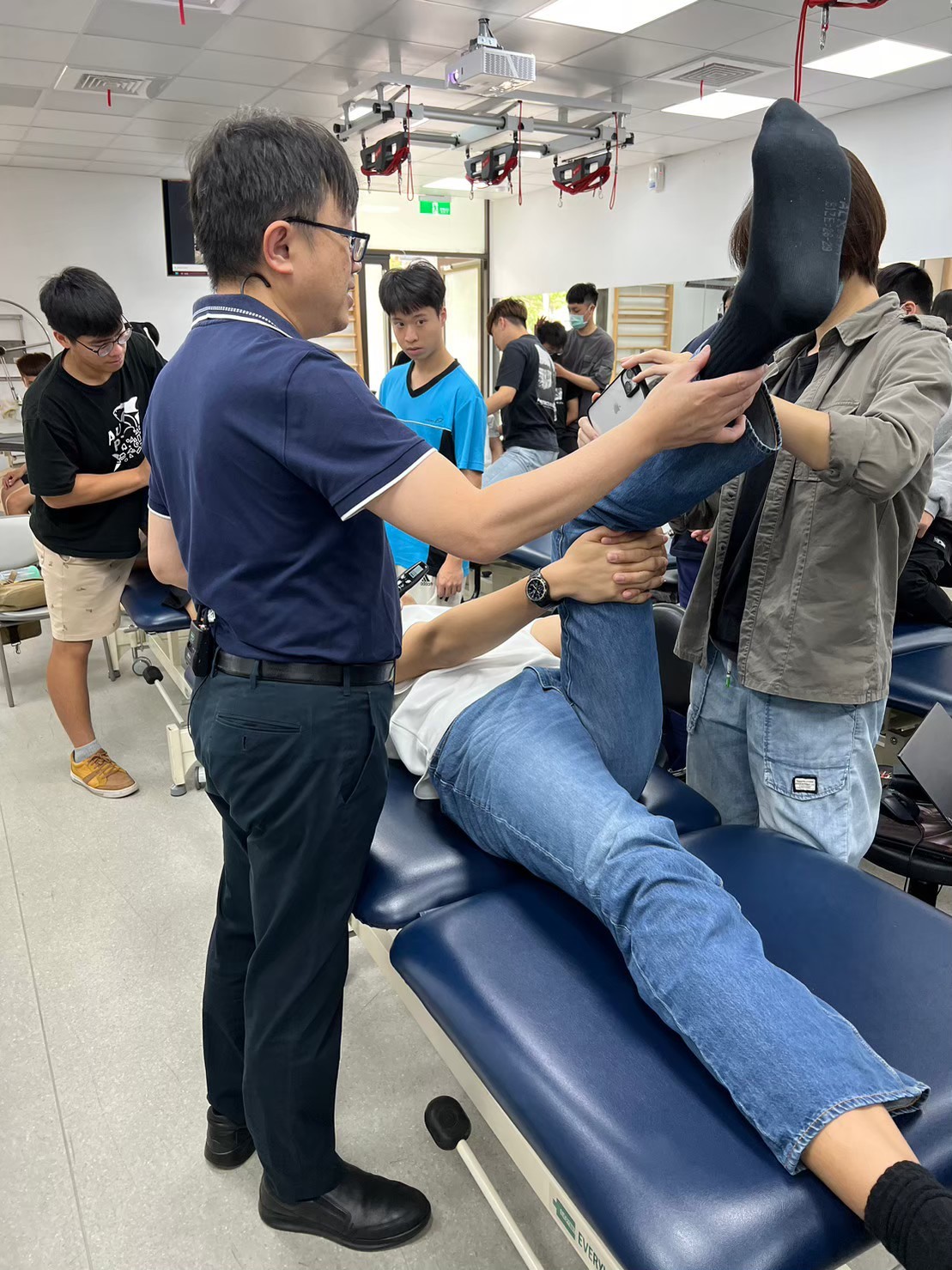 The first graduates from the Department of Physical Therapy of Asia University achieved a high pass rate in the physical therapist licensing examination. The image shows mentors guiding students through the process of physical therapy procedures